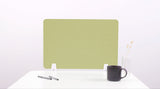 Green desk divider with rounded corners positioned on white desk with mounting brackets, black mug, pens, and white vase visi