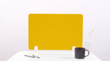 Yellow desk divider with rounded corners standing on white surface next to mug and pens.