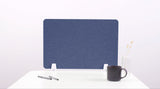 Blue desk divider panel with white mounting brackets, displayed on white desk with pen, mug, and vase.