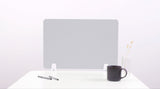 Gray desk divider with rounded corners mounted on white desk beside pen holder, mug, and vase.