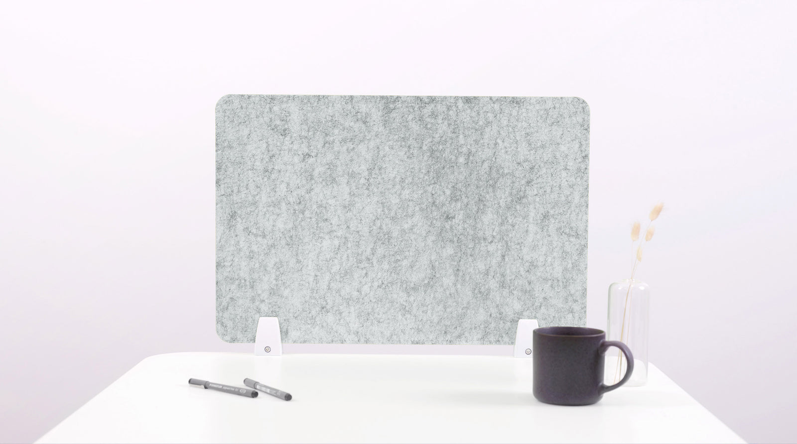 Gray felt board on a white surface with a black mug and pen.