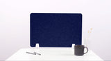 Dark blue fabric desk divider with white mounting brackets, displayed on white desk with office accessories.