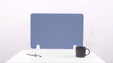 Blue desk divider with white mounting brackets on white surface, styled with pens, mug, and vase.