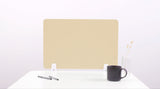 Beige desk divider with rounded corners mounted on white desk with pens, mug, and vase.