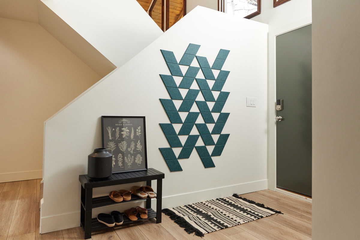 Felt Right tiles in a teal blue shade creating  a pattern on a white wall at the entry of a home with a rug and a place to put away your shoes