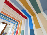 Felt right wall art design in a bedroom using shades of red, orange, blue, and cream felt tiles on a white wall and ceiling.