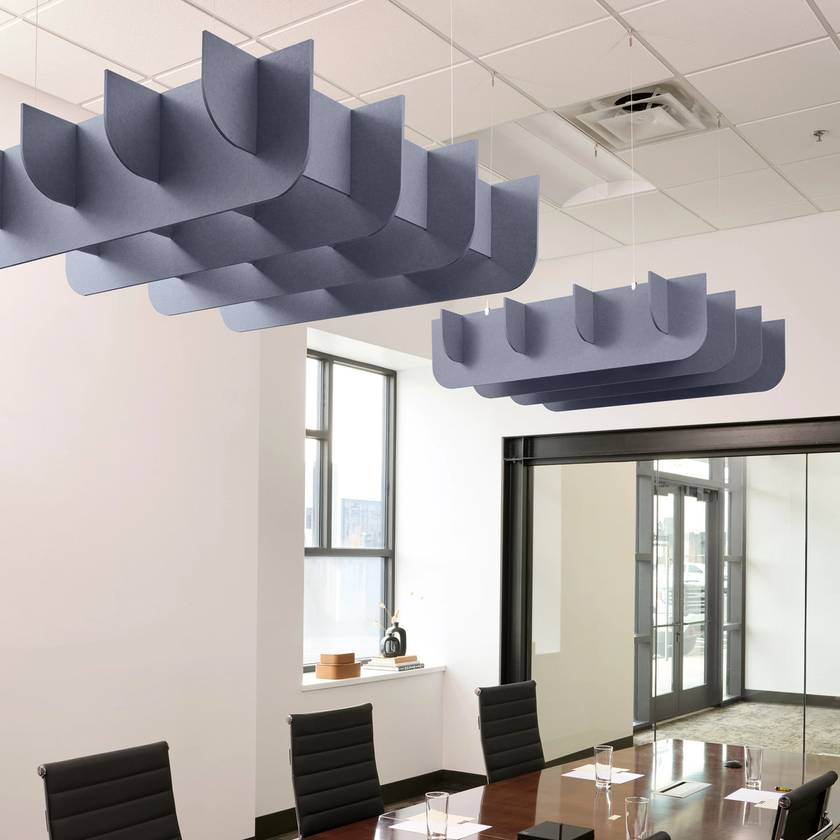 Fin 3D Cloud acoustic ceiling baffles in Periwinkle felt above a conference table