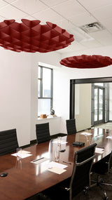 Two burgundy 3D cloud-shaped acoustic baffles suspended from ceiling in conference room above wooden table.