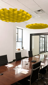 Two yellow 3D cloud-shaped baffles suspended from ceiling in modern conference room above wooden table.
