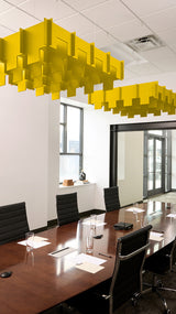 Yellow 3D cloud-shaped acoustic baffle suspended from drop ceiling in conference room above wooden table.