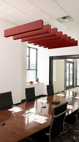 Red felt acoustic beams suspended from ceiling above conference table in modern office space.