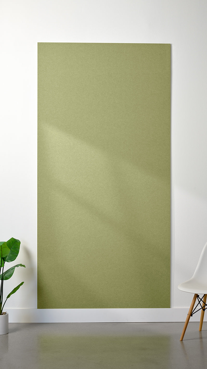 Aloe green Felt Right 4’ x 8’ PET felt panel with no engraving against a white wall. A plant and chair are in the foreground.