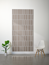 Tan and white layered felt sheet with offset engraved vertical stripe pattern mounted on wall.