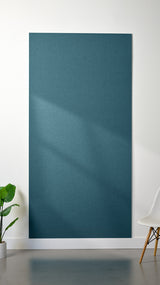 Blue Felt Right 4’ x 8’ PET felt panel with no engraving against a white wall. A plant and chair are in the foreground.