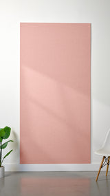 Light pink Felt Right 4’ x 8’ PET felt panel with no engraving against a white wall. A plant and chair are in the foreground.