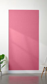 Hot pink Felt Right 4’ x 8’ PET felt panel with no engraving against a white wall. A plant and chair are in the foreground.