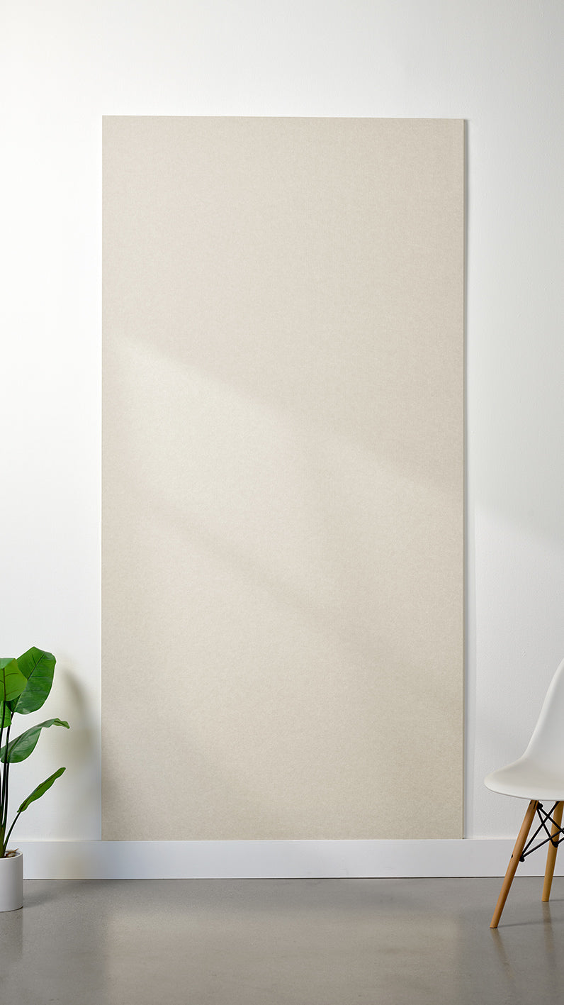 Ivory Felt Right 4’ x 8’ PET felt panel with no engraving against a white wall. A plant and chair are in the foreground.