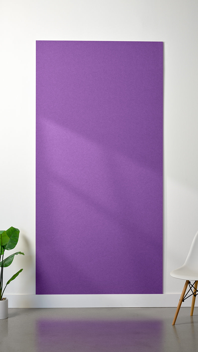 Lavender Felt Right 4’ x 8’ PET felt panel with no engraving against a white wall. A plant and chair are in the foreground.