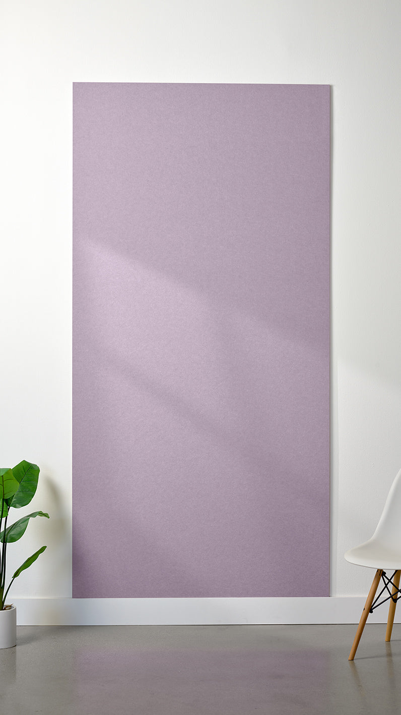 Light purple Felt Right 4’ x 8’ PET felt panel with no engraving against a white wall. A plant and chair are in the foreground.