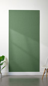 Green Felt Right 4’ x 8’ PET felt panel with no engraving against a white wall. A plant and chair are in the foreground.