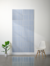 Blue-gray layered felt sheet with engraved vertical line pattern in offset arrangement displayed on wall.
