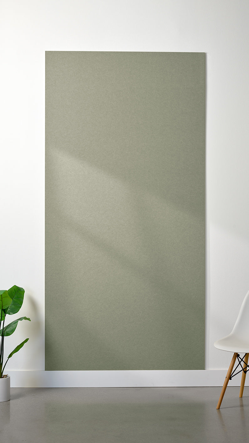 Sage green Felt Right 4’ x 8’ PET felt panel with no engraving against a white wall. A plant and chair are in the foreground.
