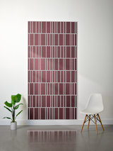 Burgundy felt sheet with white engraved geometric line pattern in offset repeating design mounted on wall.