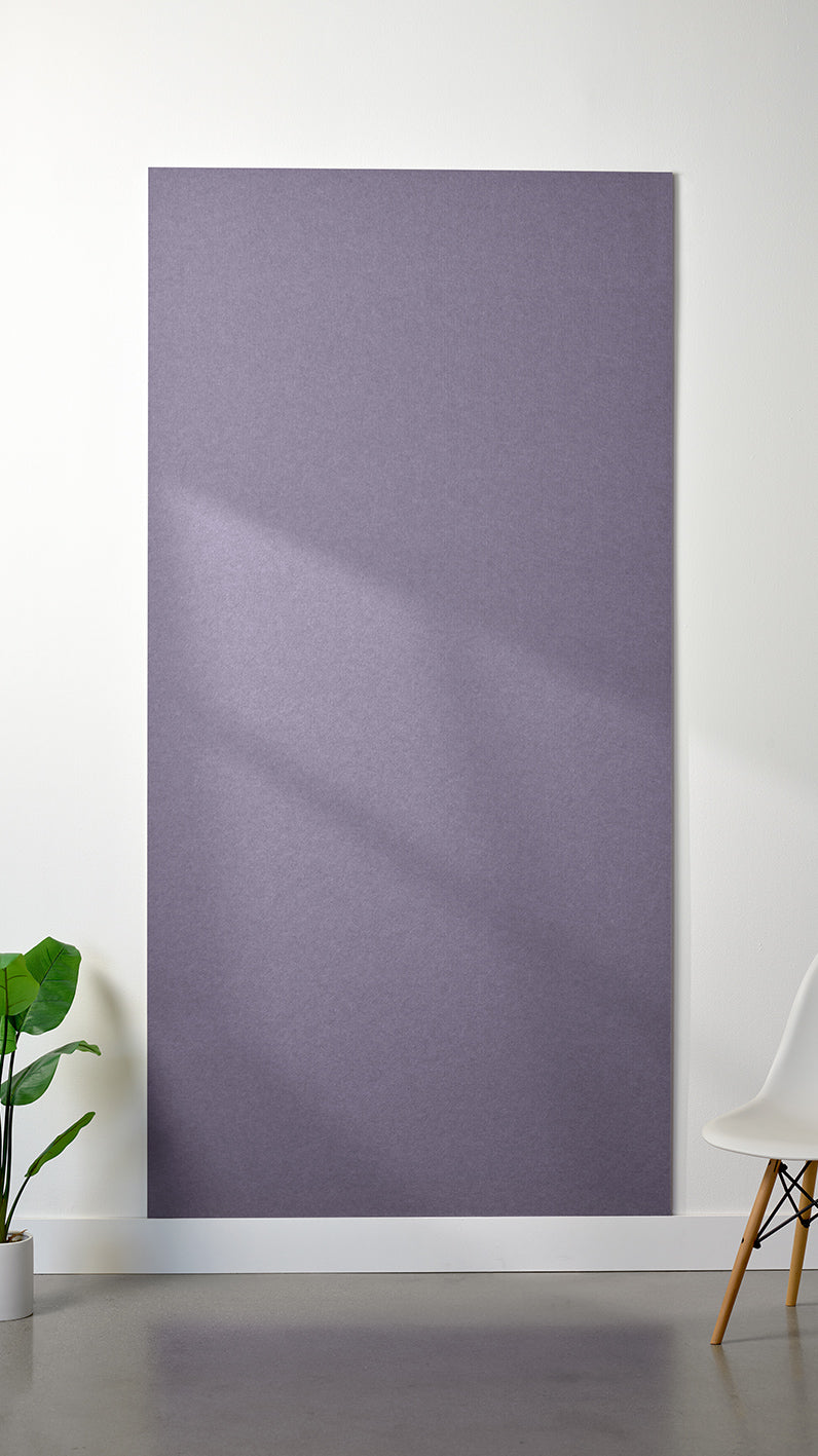 Light purple Felt Right 4’ x 8’ PET felt panel with no engraving against a white wall. A plant and chair are in the foreground.