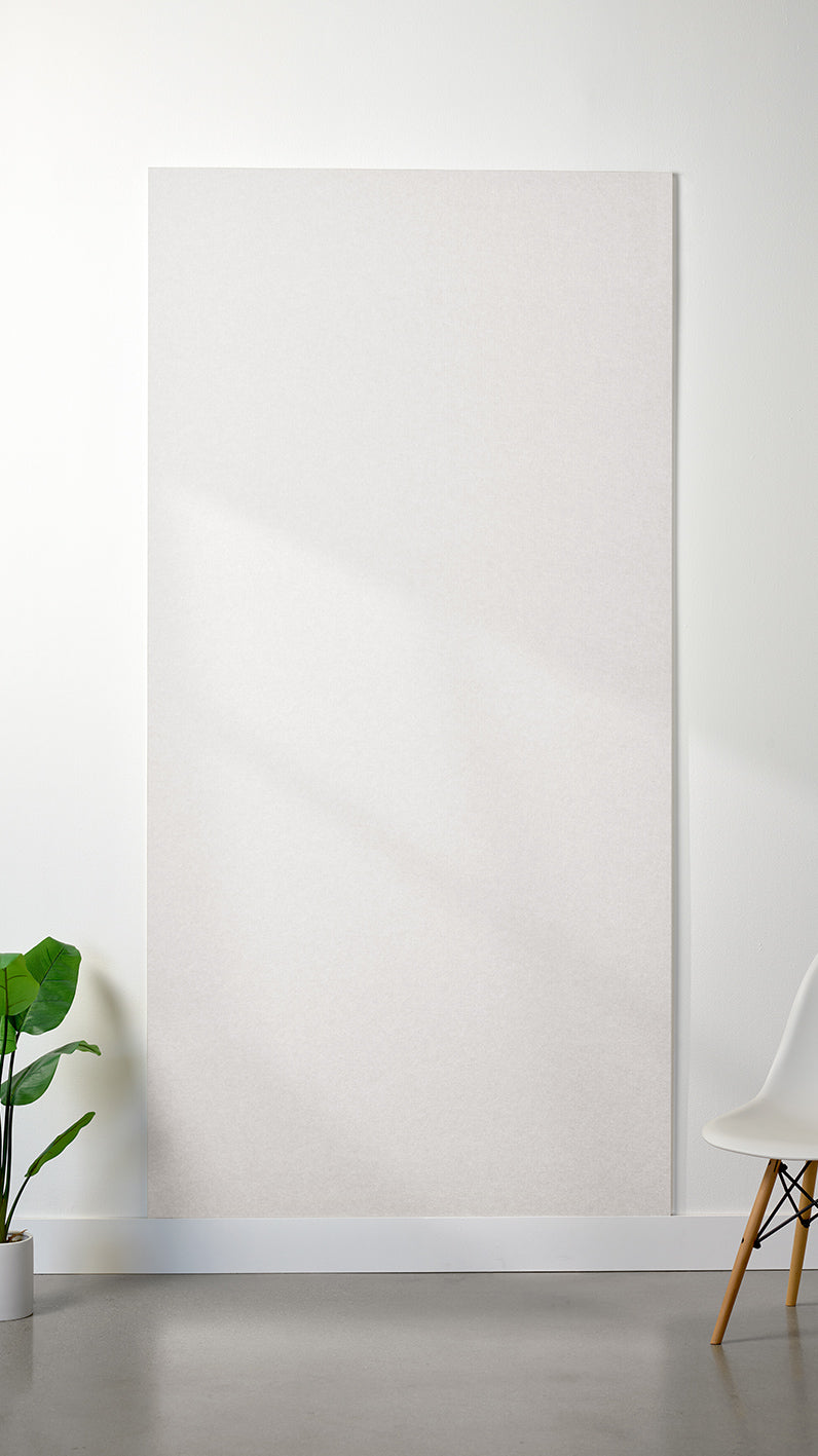 White Felt Right 4’ x 8’ PET felt panel with no engraving against a white wall. A plant and chair are in the foreground.