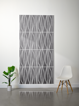 Gray and white layered felt sheet with engraved wavy vertical line pattern, displayed on white wall.