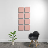 Eight pink square acoustic panels arranged in a 2x4 grid on a white wall.