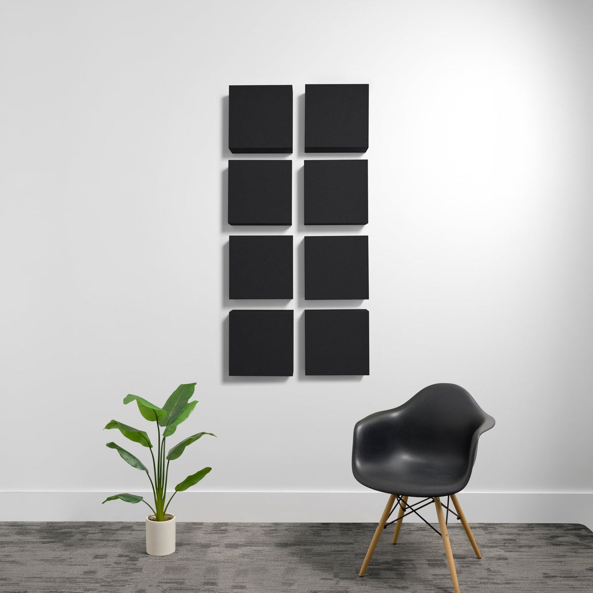 Eight black square acoustic panels arranged in a 2x4 grid on a white wall.