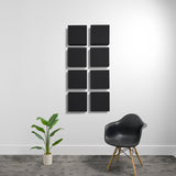 Eight black square acoustic panels arranged in a 2x4 grid on a white wall.