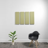 Four rectangular acoustic panels in sage green mounted on a white wall above a black chair and potted plant.