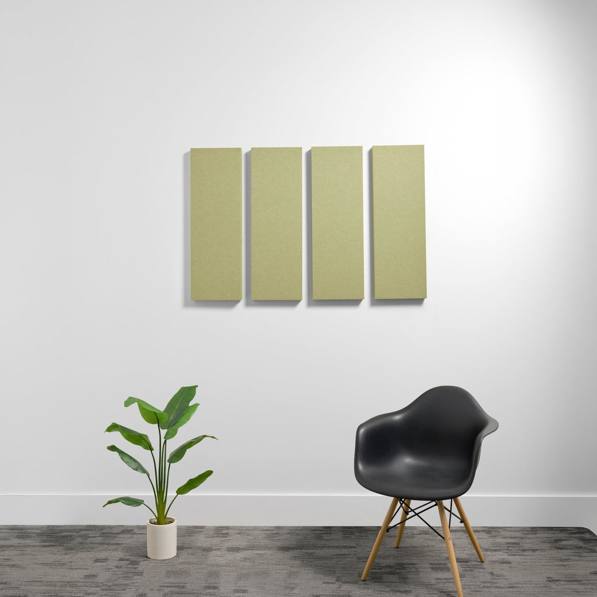 Four rectangular acoustic panels in sage green mounted on a white wall above a black chair and potted plant.