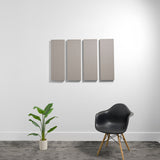Four gray rectangular 3D acoustic panels mounted on wall above a potted plant and black chair.