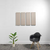 Four rectangular beige acoustic panels mounted on a white wall above a black chair and potted plant.