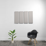 Four rectangular gray acoustic panels mounted on a white wall above a black chair and potted plant.