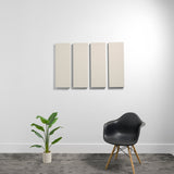 Four beige rectangular acoustic panels mounted on white wall above chair and plant.