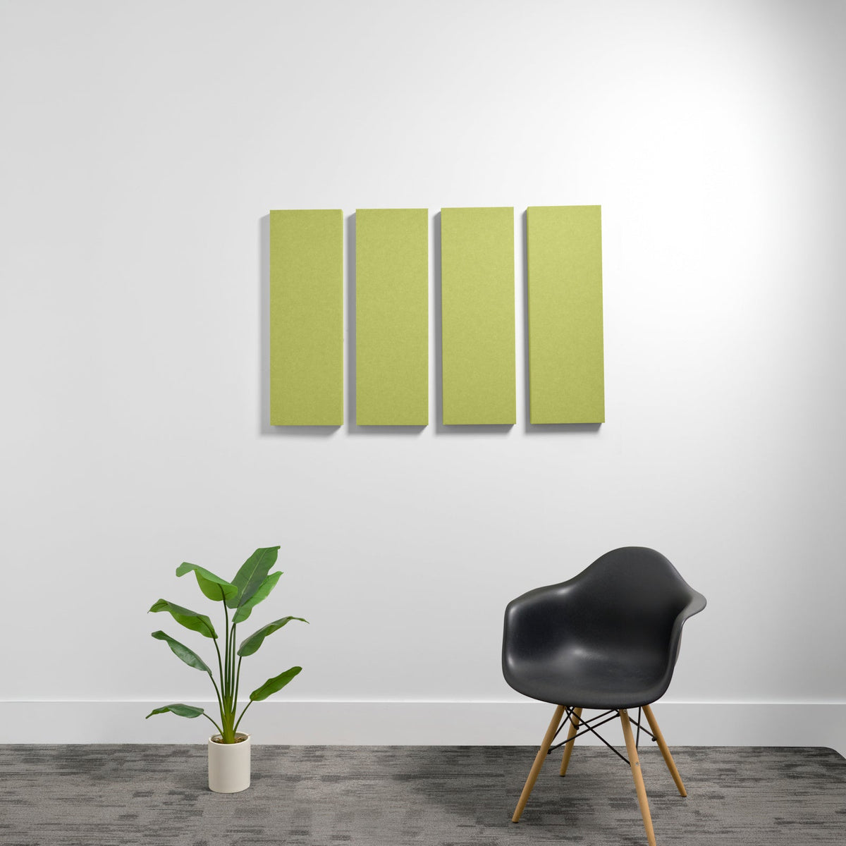 Four lime-green rectangular acoustic panels mounted on white wall above black chair and potted plant.