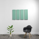 Four seafoam green rectangular acoustic panels mounted on white wall above black chair and potted plant.