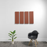 Four terracotta-colored rectangular acoustic panels mounted on wall above black chair and potted plant.