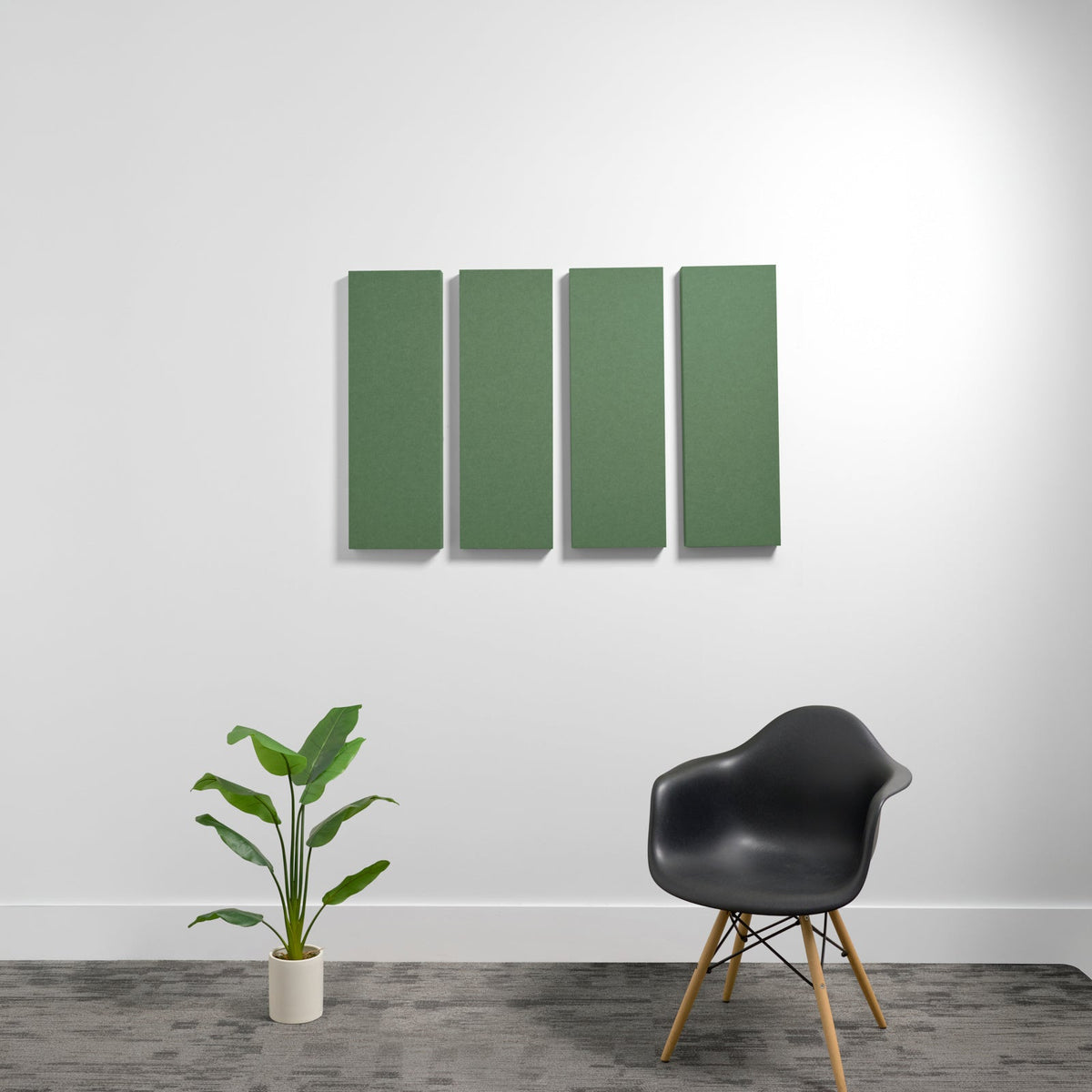 Four rectangular green acoustic wall panels mounted vertically on a white wall.