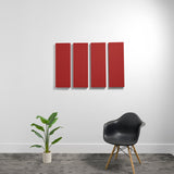 Four red rectangular 3D acoustic panels mounted on a white wall above a black chair and potted plant.
