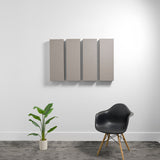 Four rectangular gray acoustic panels mounted on wall above black chair and potted plant.