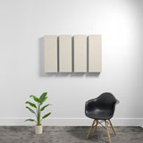 Four cream-colored rectangular acoustic panels mounted on wall above black chair and potted plant.