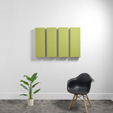 Four rectangular green acoustic panels mounted on wall in a room with black chair and potted plant.