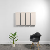 Four beige rectangular acoustic panels mounted on wall above black chair and potted plant.