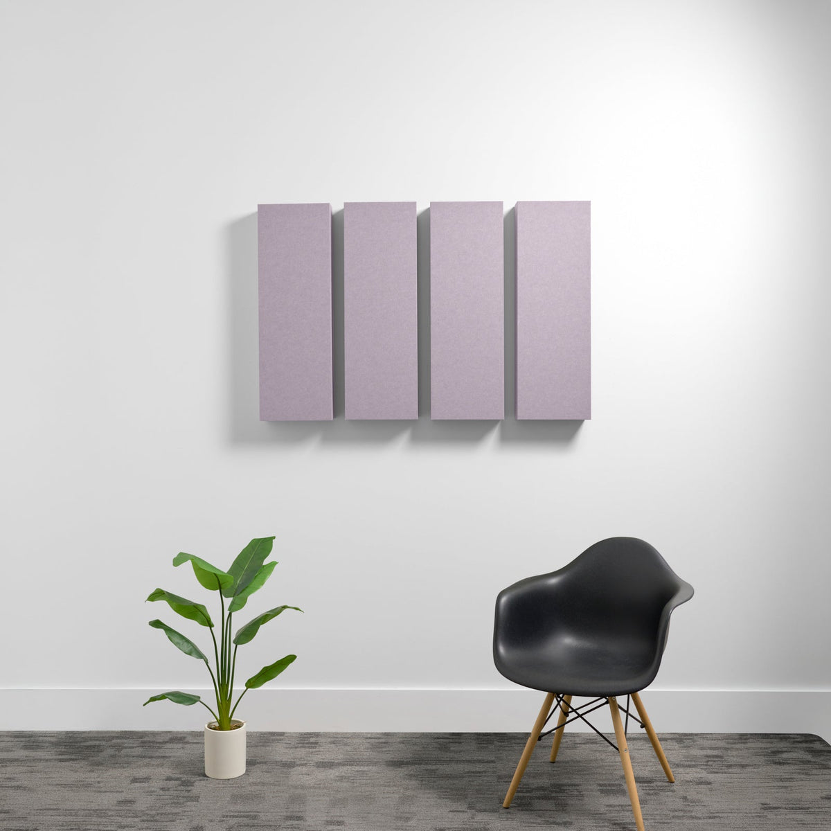 Four rectangular mauve acoustic panels mounted on white wall above black chair and potted plant.