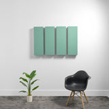 Four rectangular sage green acoustic panels mounted on white wall above black chair and potted plant.